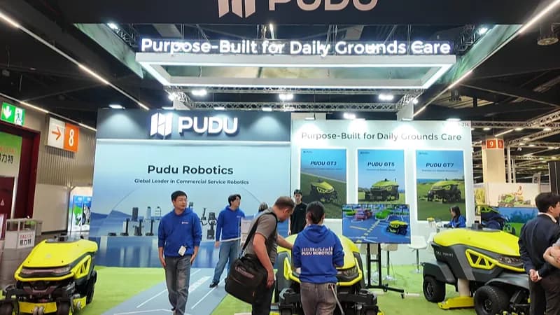 Le stand Pudu Robotics au salon GaLaBau 2026 à Nuremberg, avec des visiteurs autour des tondeuses robots PUDU GT5 et GT7 exposées.